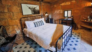 A rustic room with a bed, a desk, and a chair.