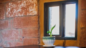 A dark wooden table with two matching chairs, a small potted plant, and a window with a view of the outside.