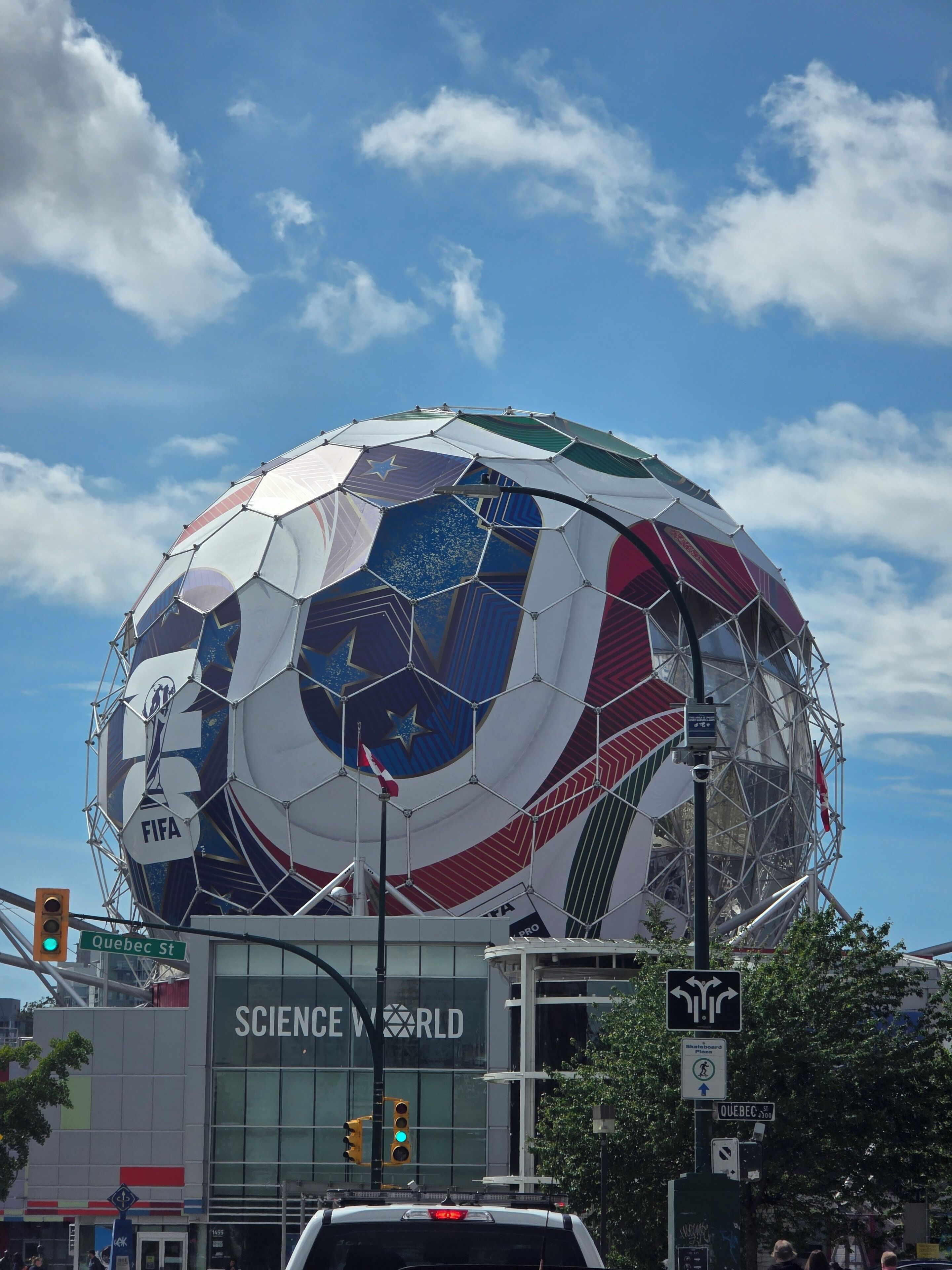 Uma grande estrutura esférica com o logotipo da FIFA, rodeada por um edifício moderno com a inscrição 'SCIENCE WORLD'.