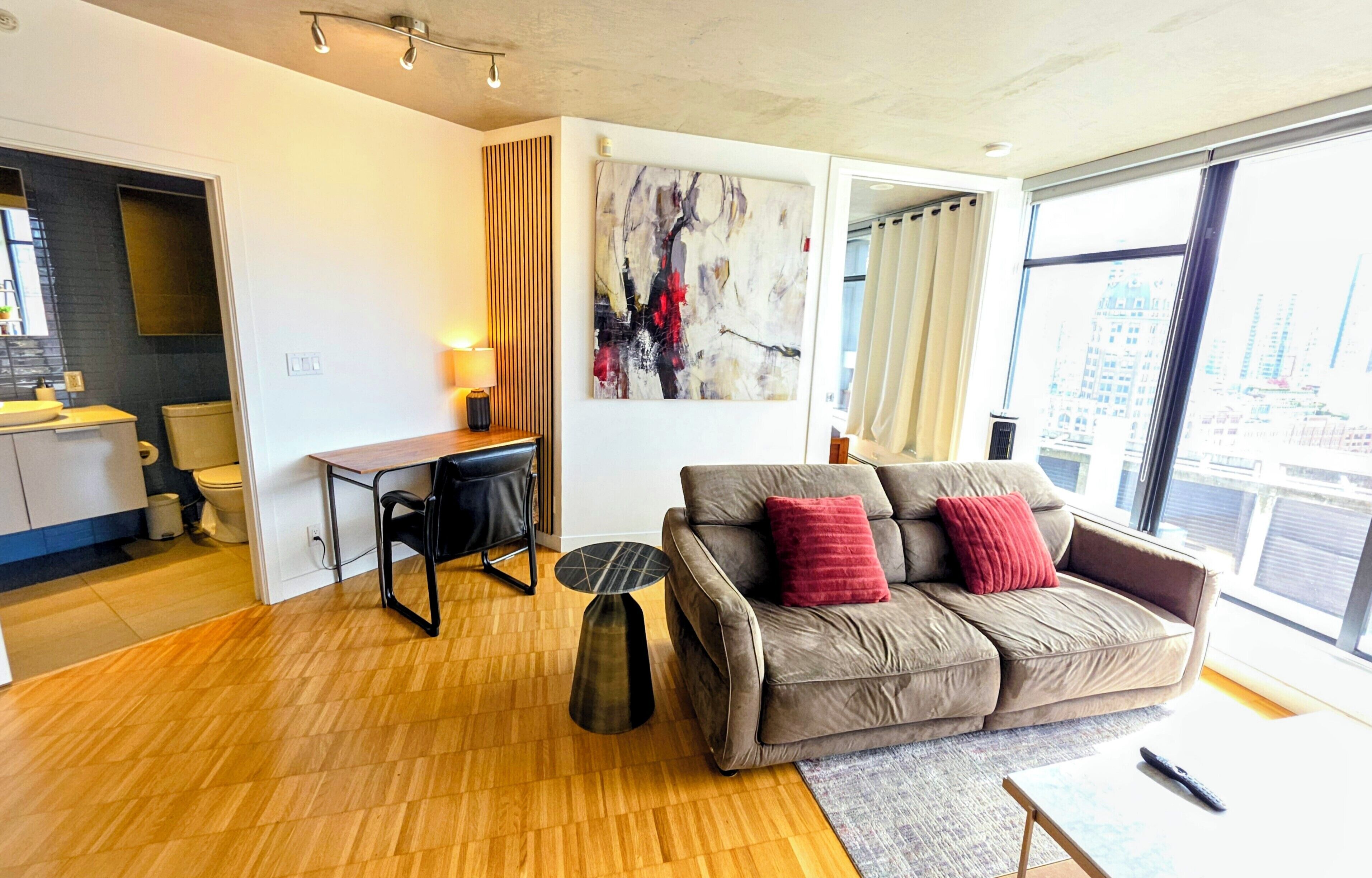 Ein modernes Wohnzimmer mit einer Couch, einem kleinen Tisch, einer Lampe und einem Gemälde an der Wand.