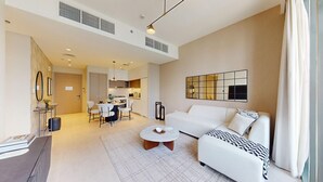 A modern living room with a white sofa, a coffee table, and a dining area with chairs and a table. - Creek Edge - One Bedroom with Partial Sea View (Creek Harbour)