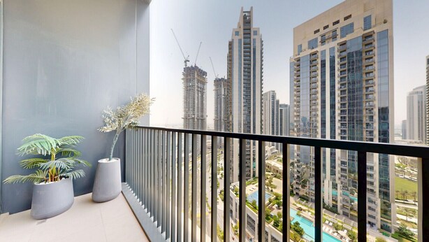 A balcony with a view of high-rise buildings and a swimming pool. - Creek Edge - One Bedroom with Partial Sea View (Creek Harbour)