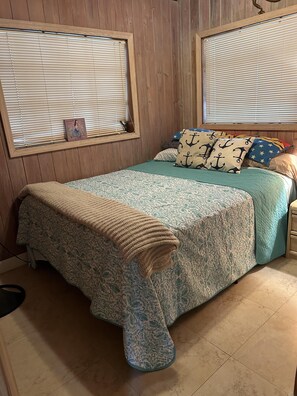 A bedroom with a bed, wooden walls, and a window with blinds. - Deep Water Home located in White Marlin Beach Neighborhood (Islamorada)