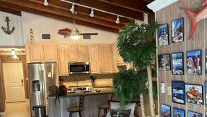 A spacious kitchen with wooden cabinets, a stainless steel refrigerator, and a microwave. There is a dining area with a wooden chair and a table. - Deep Water Home located in White Marlin Beach Neighborhood (Islamorada)