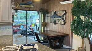 A kitchen with granite countertops, wooden cabinets, a dining table, and a potted plant. - Deep Water Home located in White Marlin Beach Neighborhood (Islamorada)