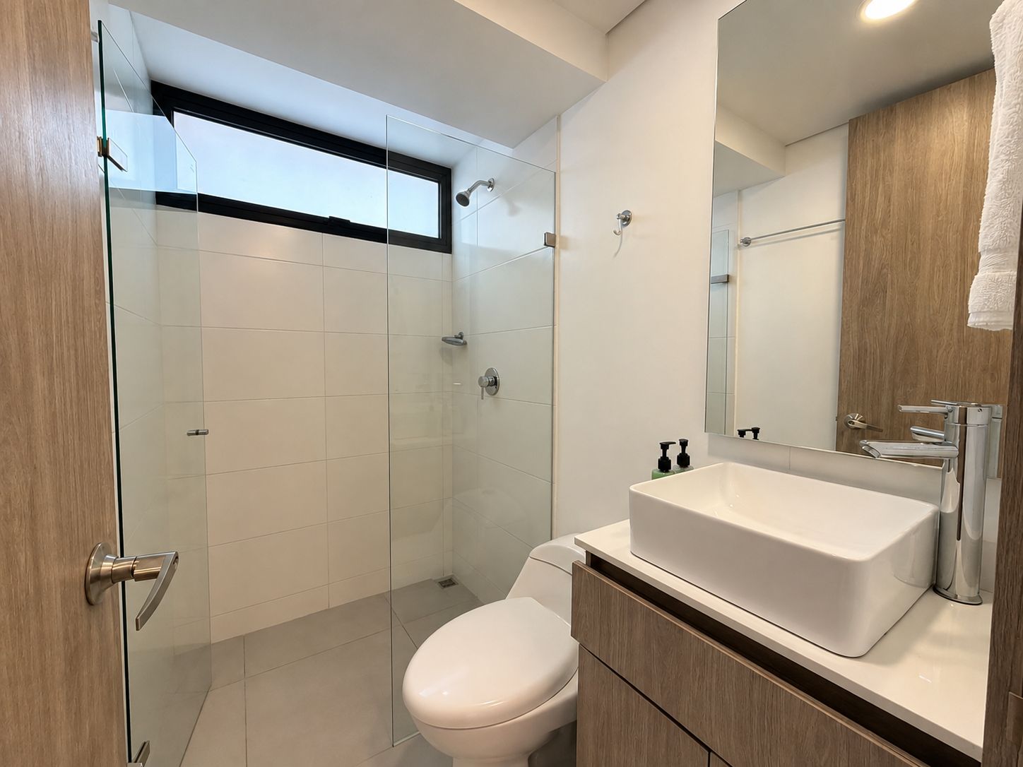 A modern bathroom with a glass shower enclosure, a white sink, and a toilet.