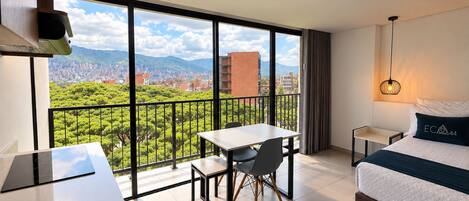 Habitación de hotel con balcón, cama, escritorio y silla.