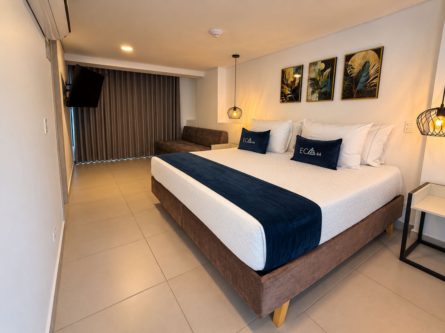 Une chambre d’hôtel moderne équipée d’un grand lit, d’un canapé et d’un téléviseur à écran plat.