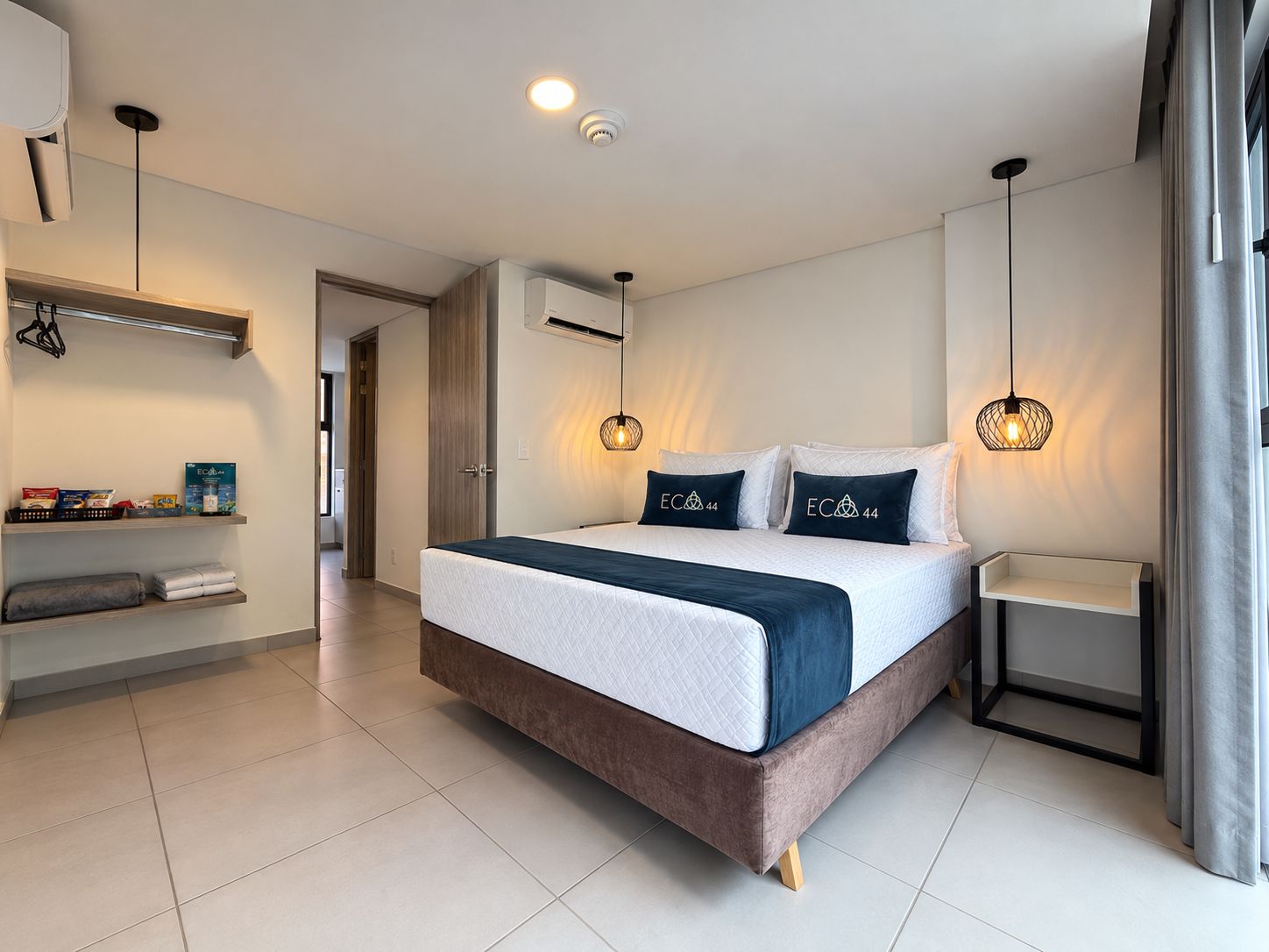 Een moderne hotelkamer met een groot bed, nachtkastjes, een kledingkast en een badkamer die door een open deur zichtbaar is.
