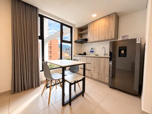 Una cocina moderna con una mesa y sillas, un refrigerador y vistas a edificios.