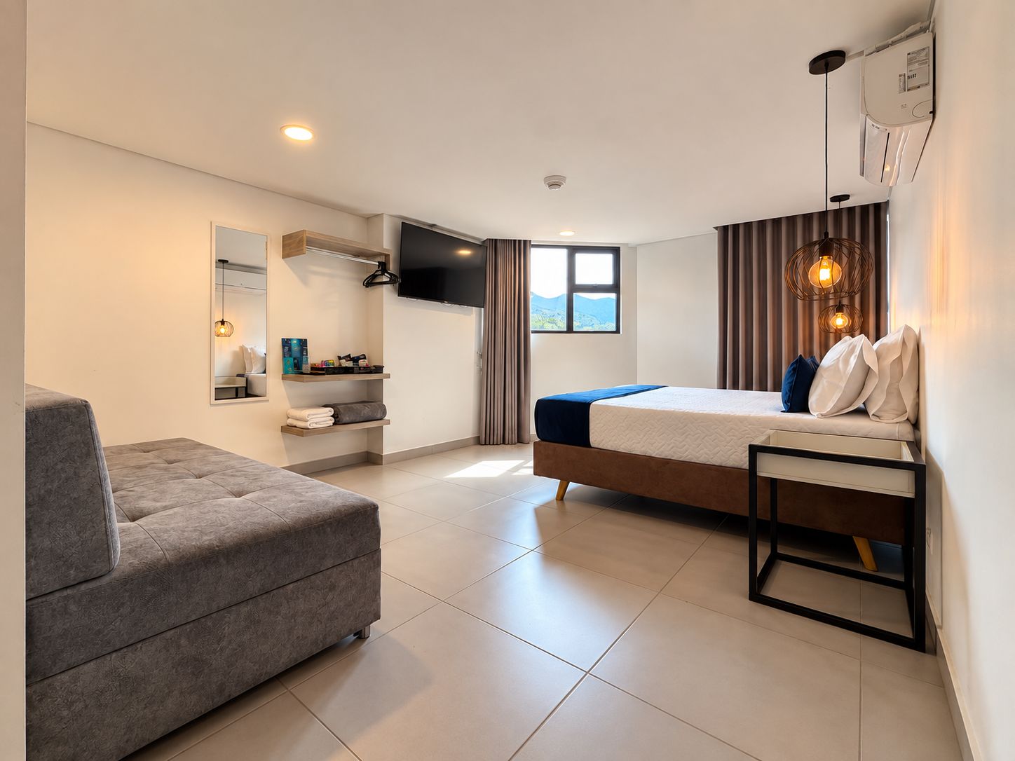 Une chambre d’hôtel moderne équipée d’un lit, d’un canapé, d’une télévision et d’une salle de bain.