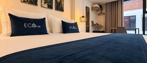 A hotel room with a large bed, a desk, and a window with curtains.