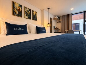 A hotel room with a large bed, a desk, and a window with curtains. - Hotel ECO 44 (Medellín)