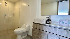 A modern bathroom with a toilet, a sink, and a mirror. - Hotel ECO 44 (Medellín)