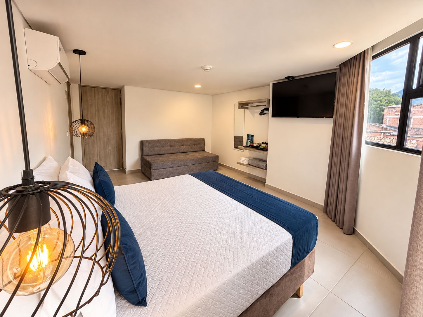 A modern bedroom with a bed, bedside lamp, and a TV.