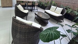 A modern outdoor seating area with wicker furniture, a flat-screen TV, and potted plants. - Hotel ECO 44 (Medellín)