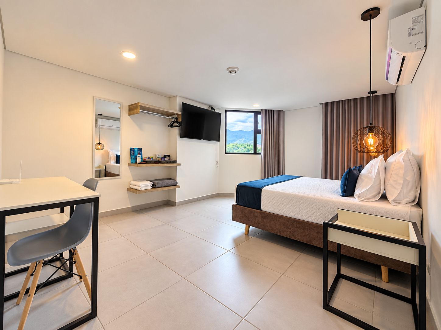 A modern hotel room with a bed, a desk, a chair, a TV, and a window with a view.