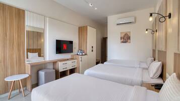 A hotel room with two beds, a desk with a TV, a small table, and a wardrobe.
