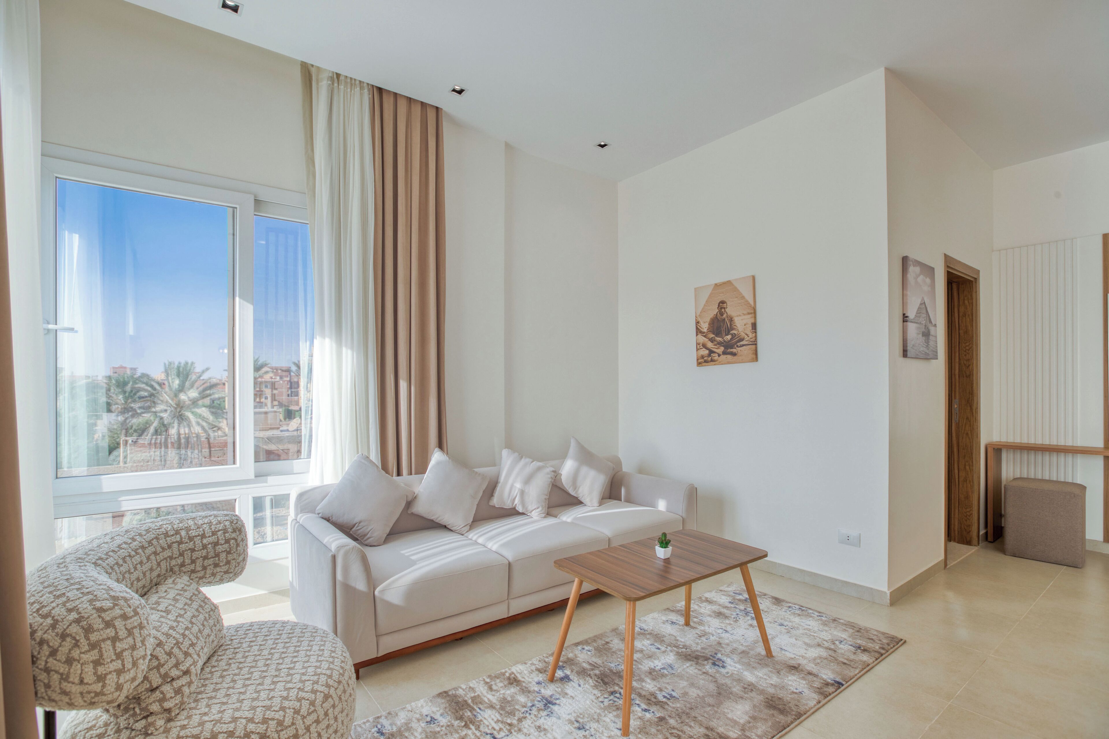 Una sala de estar moderna con un sofá, una mesa de centro y vistas a palmeras al exterior.