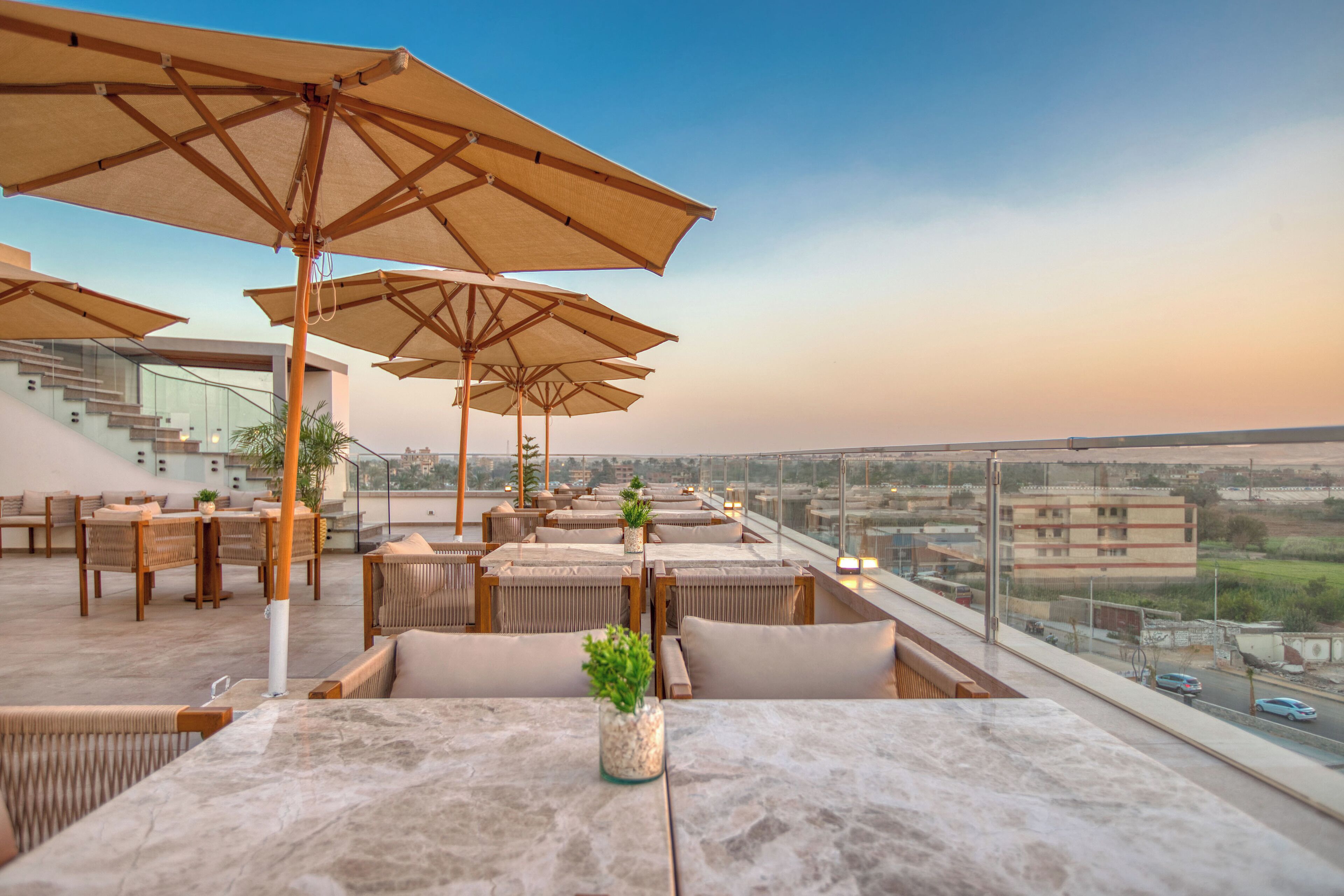 A rooftop terrace with outdoor seating, umbrellas, and a view of the cityscape.