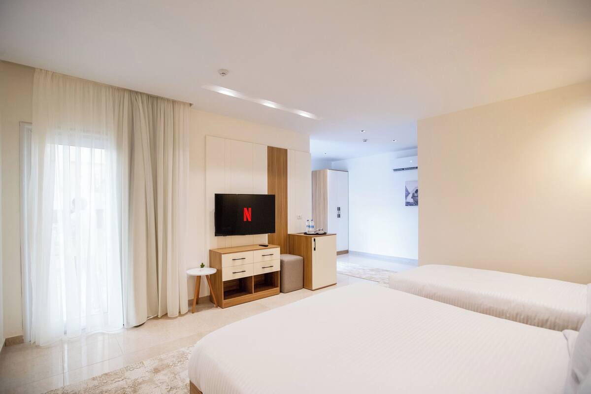 A hotel room with a large bed, a TV, a small desk, and a wardrobe.
