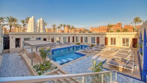A rooftop pool area with lounge chairs, a swimming pool, and palm trees. - Mazar Pyramids Hotel (Giza)