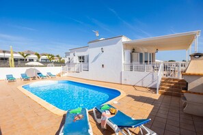 A swimming pool with lounge chairs, a covered seating area, and a staircase leading to an upper level. - Villa Gaida in Puerto Calero (Yaiza)