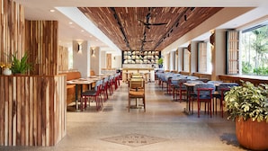 A spacious restaurant with a long counter, wooden paneling on the walls, and a central seating area with chairs and tables. - Classic Room with King Bed – Design-Centric Space (Honolulu)