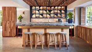 Ein moderner Barbereich mit Holzbalkendecke, einer Bar und vier Korbstühlen.