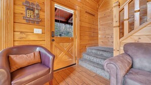Ein Holzblockbau-Innenraum mit Holztür, einer Treppe und zwei Ledersofas.
