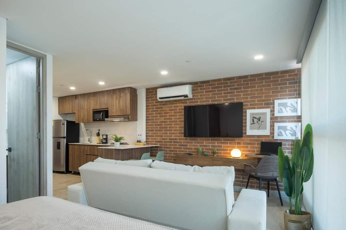 A modern apartment with a kitchen, dining area, and a living room with a sofa and a TV.