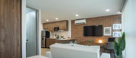 A modern apartment with a kitchen, dining area, and a living room with a sofa and a TV.