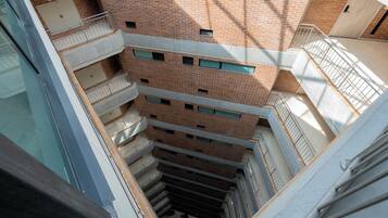 Un immeuble à plusieurs étages, doté d’une façade en briques, de nombreux balcons et d’un atrium central.