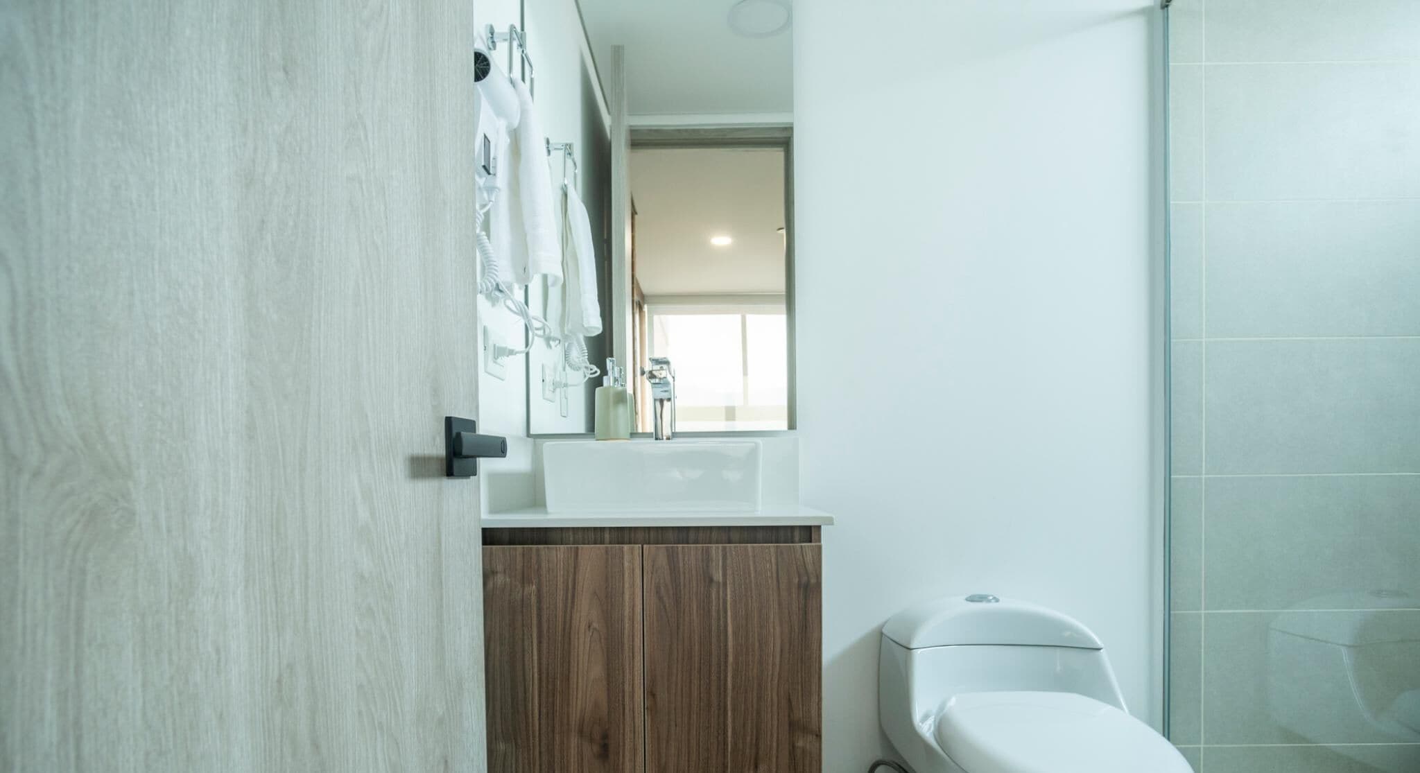 Un bagno moderno con un mobile bagno in legno, un lavandino bianco e un water.