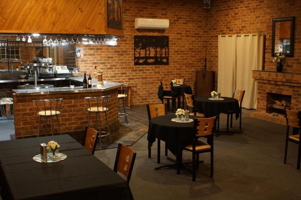 Un restaurant aux murs en briques, doté d’un bar et de plusieurs tables à manger avec des chaises.
