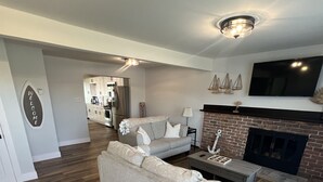 Un salon moderne avec un grand canapé, une cheminée et un téléviseur fixé au mur.
