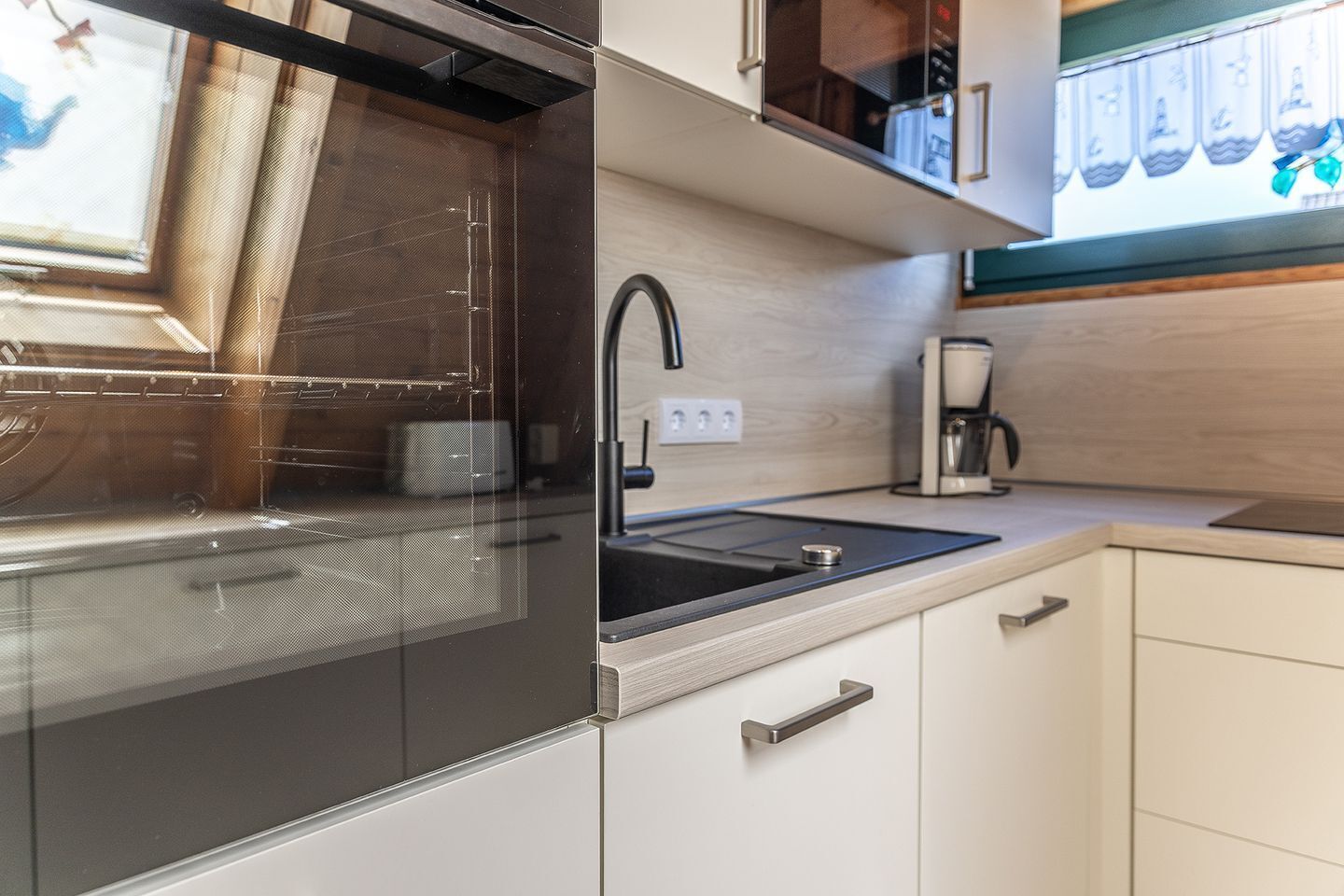 Een moderne keuken met een inbouwoven, een spoelbak en een koffiezetapparaat.