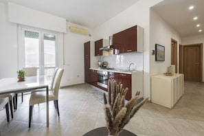 A modern kitchen with dark cabinets, a central island, and a dining area with chairs.