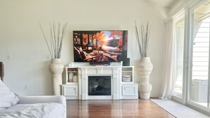 A living room with a fireplace, a television, and a large window. - The Cove on Conroe Lakefront Oasis (Montgomery)