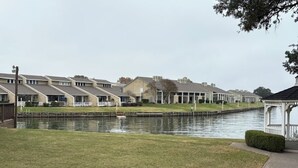A row of uniform buildings with a canal in the foreground. - The Cove on Conroe Lakefront Oasis (Montgomery)