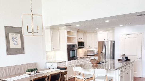 A modern kitchen with white cabinetry, stainless steel appliances, and a central island. - The Cove on Conroe Lakefront Oasis (Montgomery)