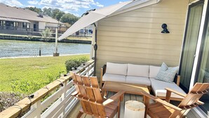A deck with a sofa, chairs, and a round table. - The Cove on Conroe Lakefront Oasis (Montgomery)