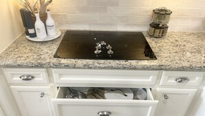 A kitchen with a black stovetop, white cabinets, and a granite countertop. - The Cove on Conroe Lakefront Oasis (Montgomery)