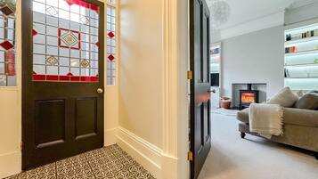 Un pasillo con piso estampado que lleva a una habitación con chimenea y sofá.