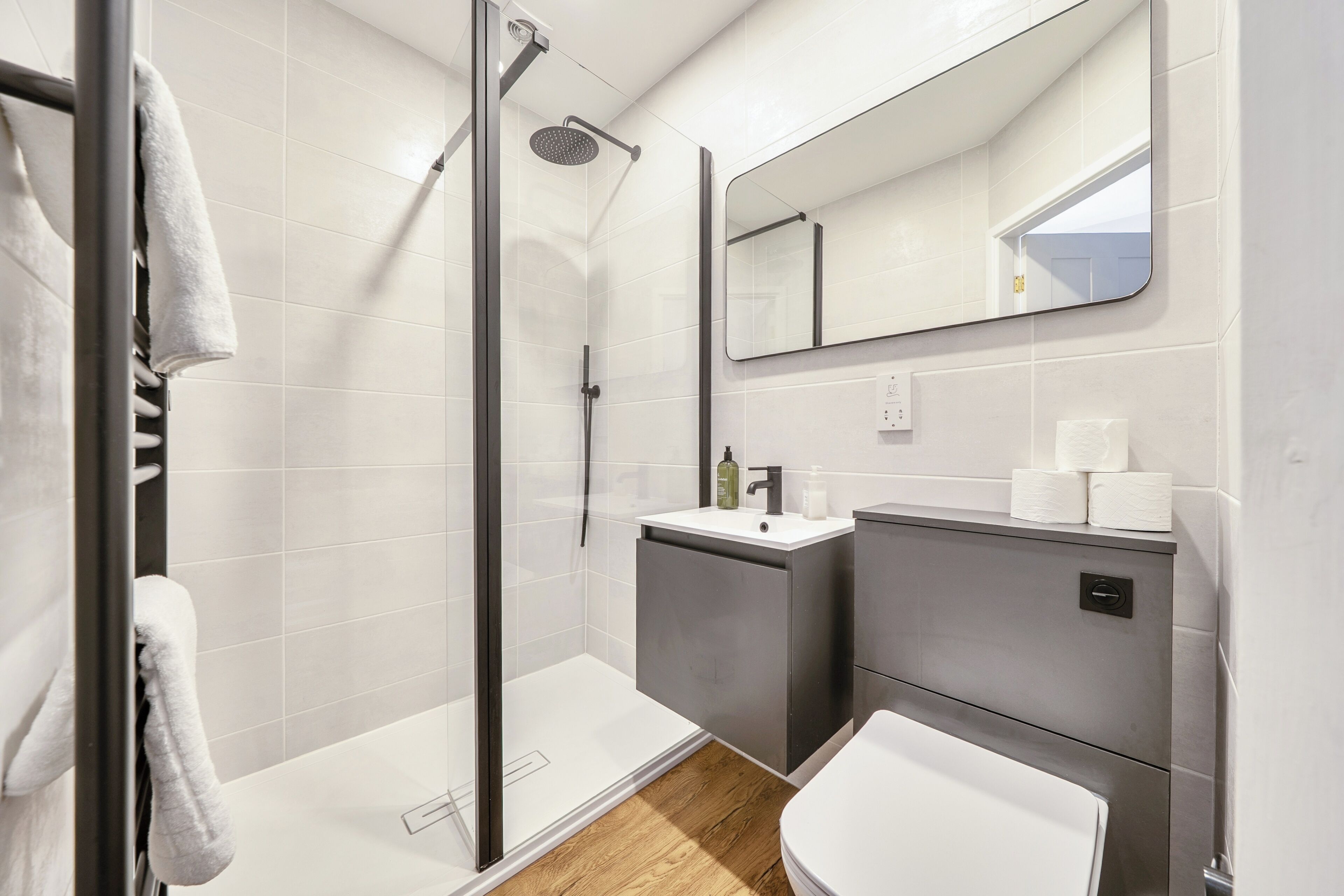 A modern bathroom with a glass-enclosed shower, a white sink, and a toilet.