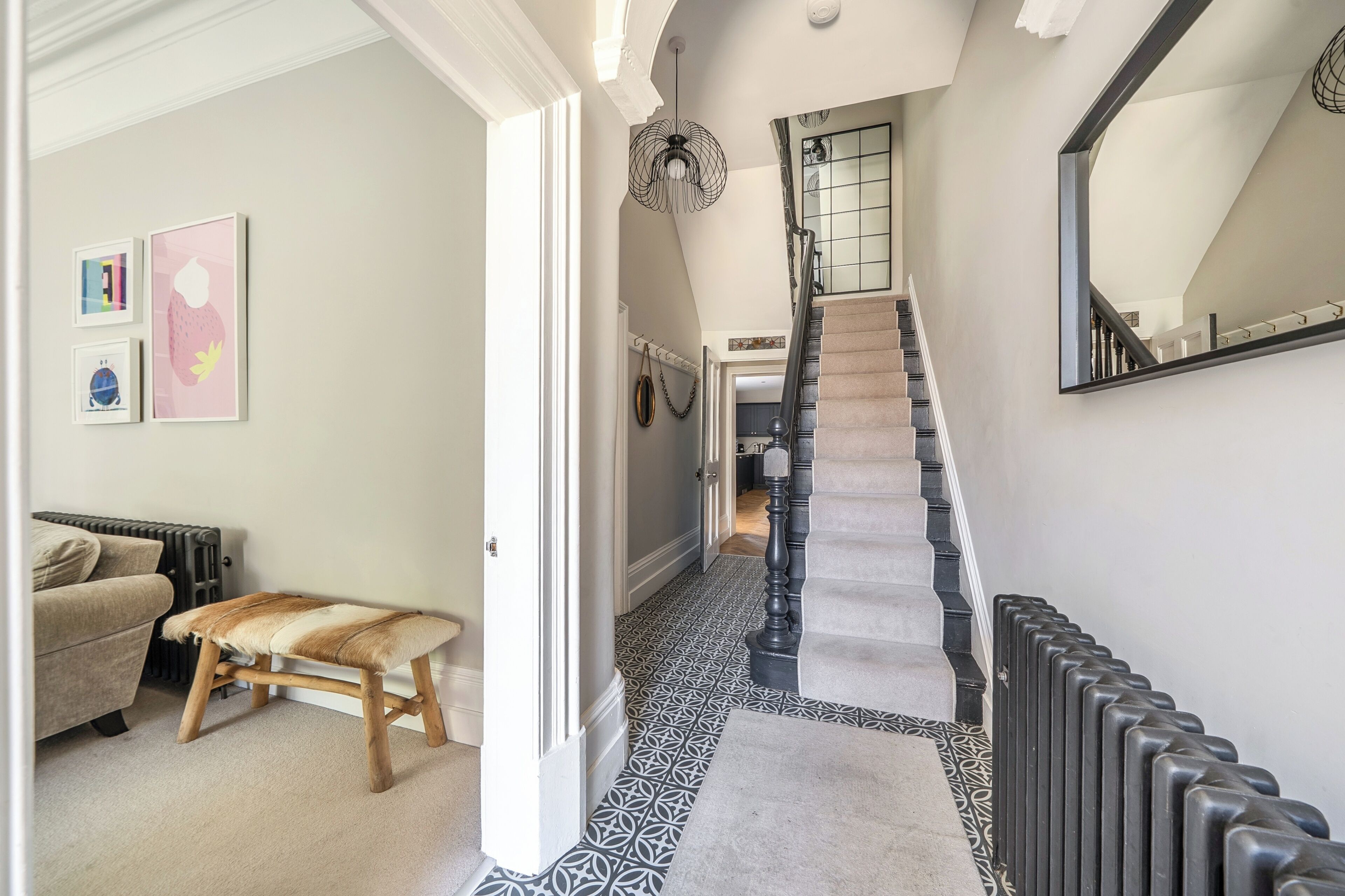 A hallway with a staircase, a bench, and a radiator.