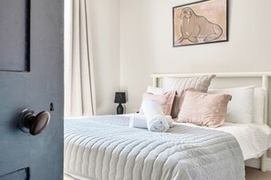Une chambre à coucher avec un lit, des oreillers, une lampe de chevet et une œuvre d’art murale.