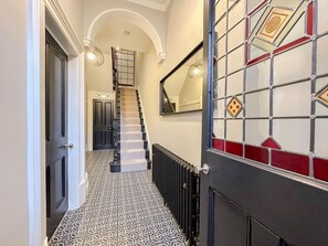 A hallway with a patterned floor, a staircase, and a door with a geometric design. - Victorian Beach House in Saltburn By The Sea (Saltburn-by-the-Sea)