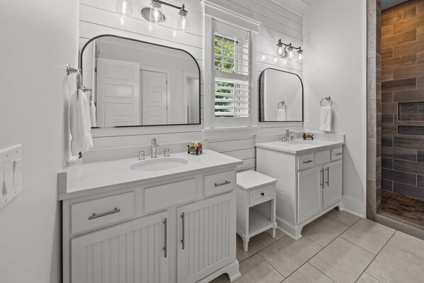 Une salle de bain avec deux lavabos, un miroir et un espace douche.