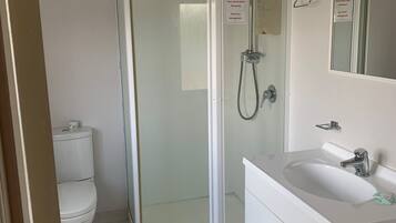 Eenvoudige tweepersoonskamer | Badkamer | Een douche, handdoeken, zeep, toiletpapier